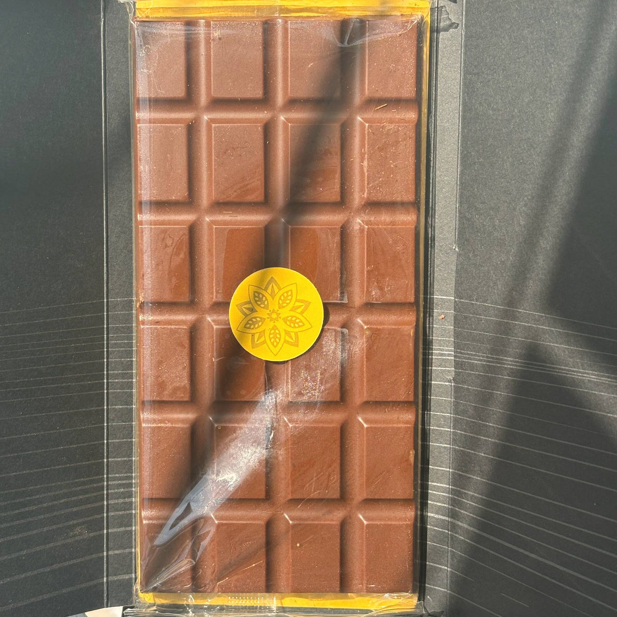 An Oro bar unwrapped from its black sleeve, the chocolate with a gold Oro seal, seen from above