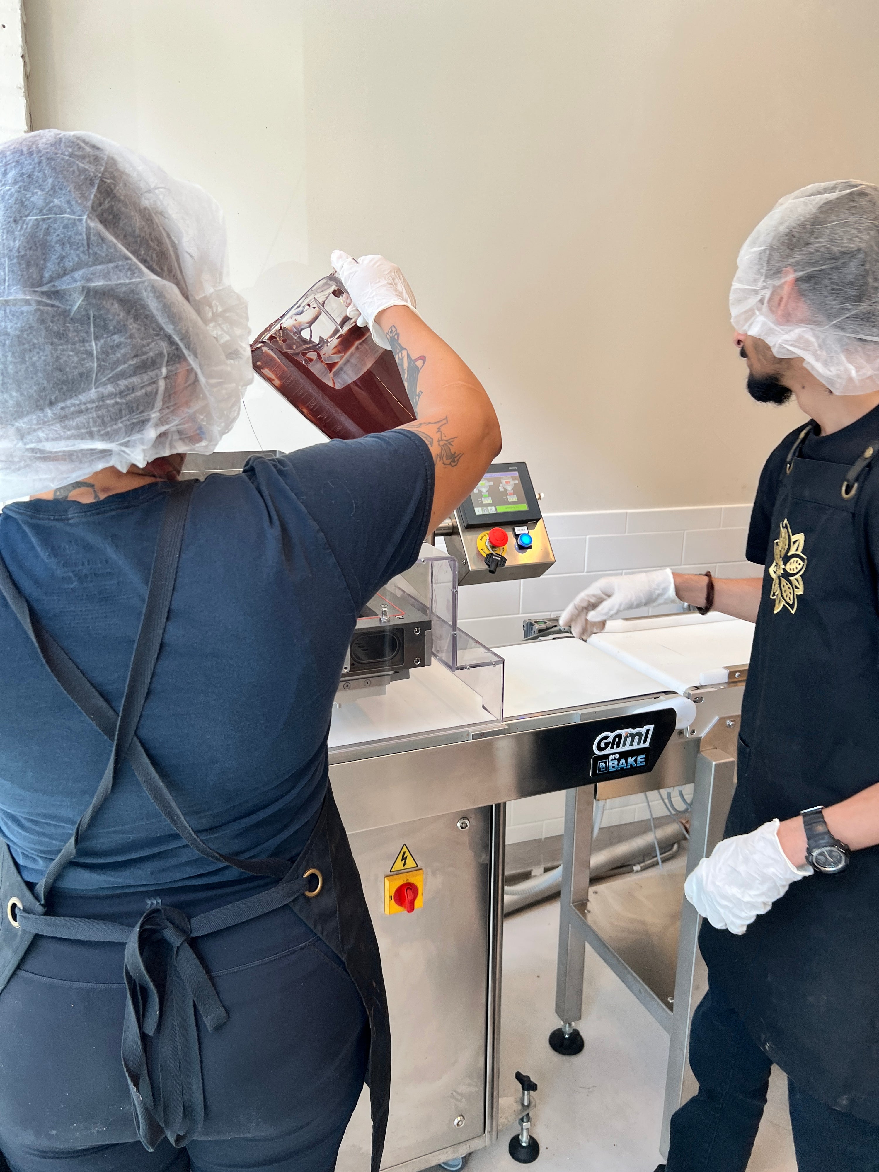 Oro chocolate makers pouring cacao into the melanger in our Wicker Park shop