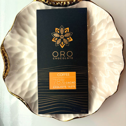 Oro Coffee 78% cacao bar in black packaging on a gold-rimmed white porcelain plate, seen from above