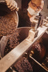 A chocolate maker pouring cacao nibs into the stone melangeur at Oro&