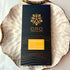 Oro Golden Milk 62% cacao bar in black packaging on a gold-rimmed white porcelain plate, seen from above