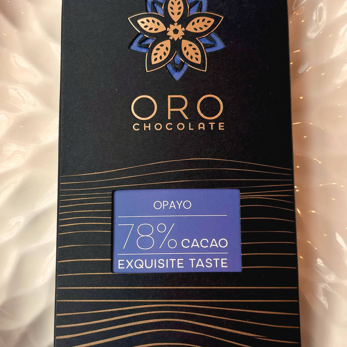 Close-up of the Oro Opayo 78% cacao chocolate bar label and the gold Oro flower mark on the black pack
