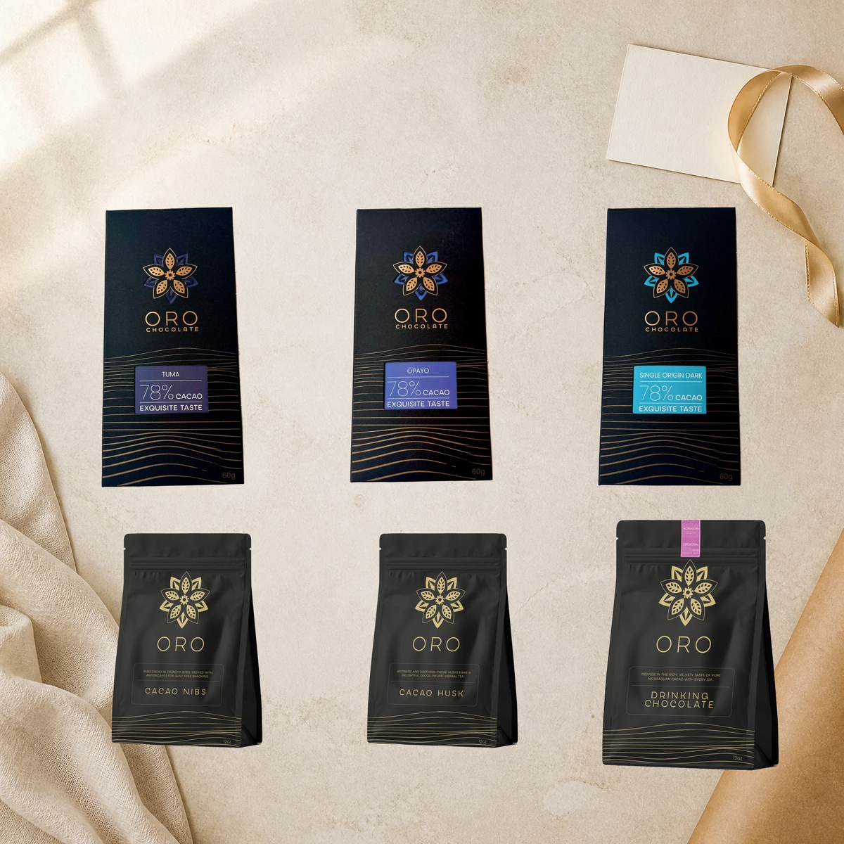 Oro Connoisseur editorial gift setting: Tuma, Opayo and Single Origin Dark 78% bars, nibs, husk tea and Ceremonial 100% drinking chocolate beside cream linen, a blank note card and gold ribbon.