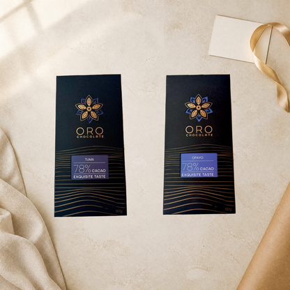 Oro Flight editorial gift setting: Tuma and Opayo 78% cacao bars, 60g each, beside cream linen, a blank note card and gold ribbon.