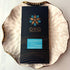 Oro Single Origin Dark 78% cacao bar in black packaging on a gold-rimmed white porcelain plate, seen from above