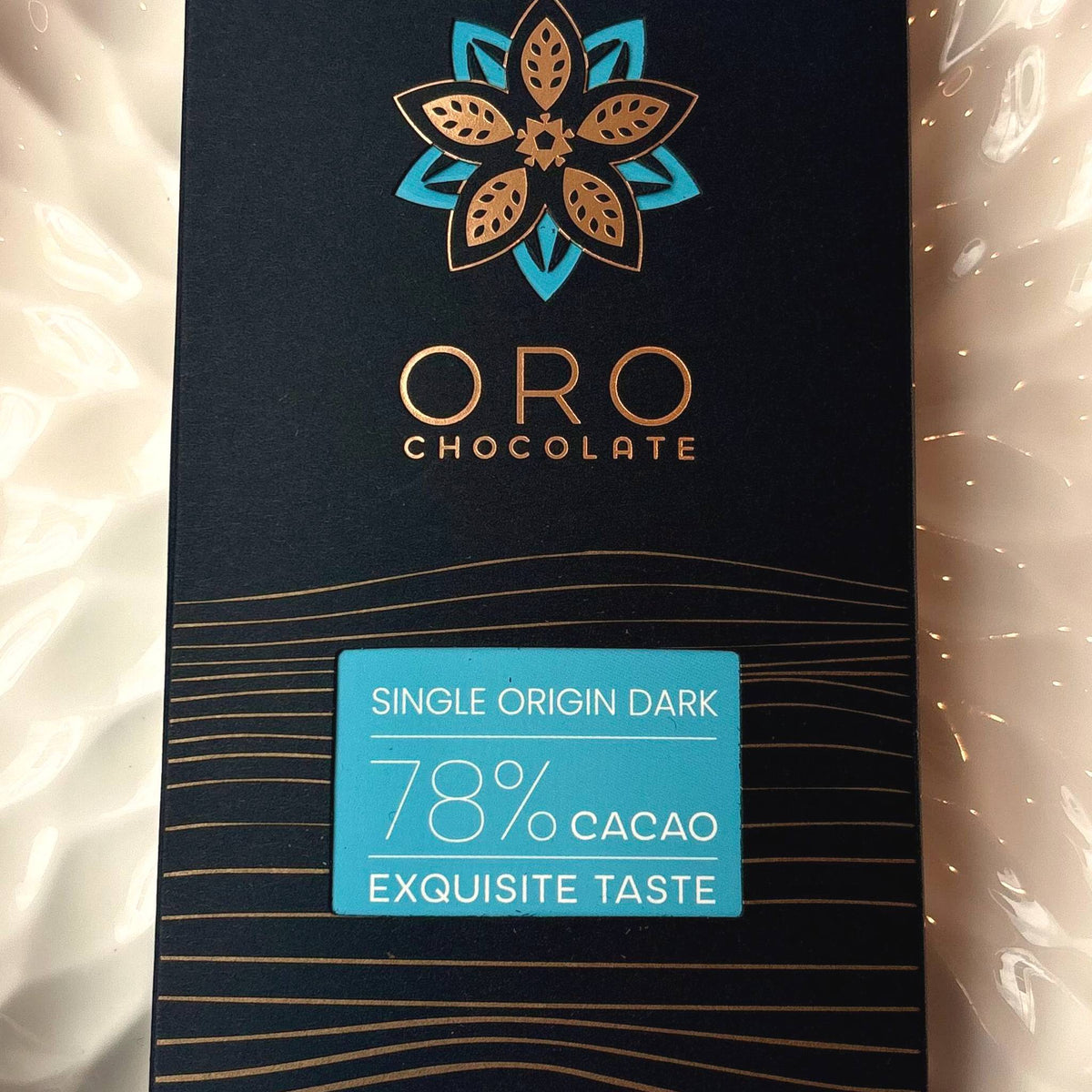 Close-up of the Oro Single Origin Dark 78% cacao chocolate bar label and the gold Oro flower mark on the black pack