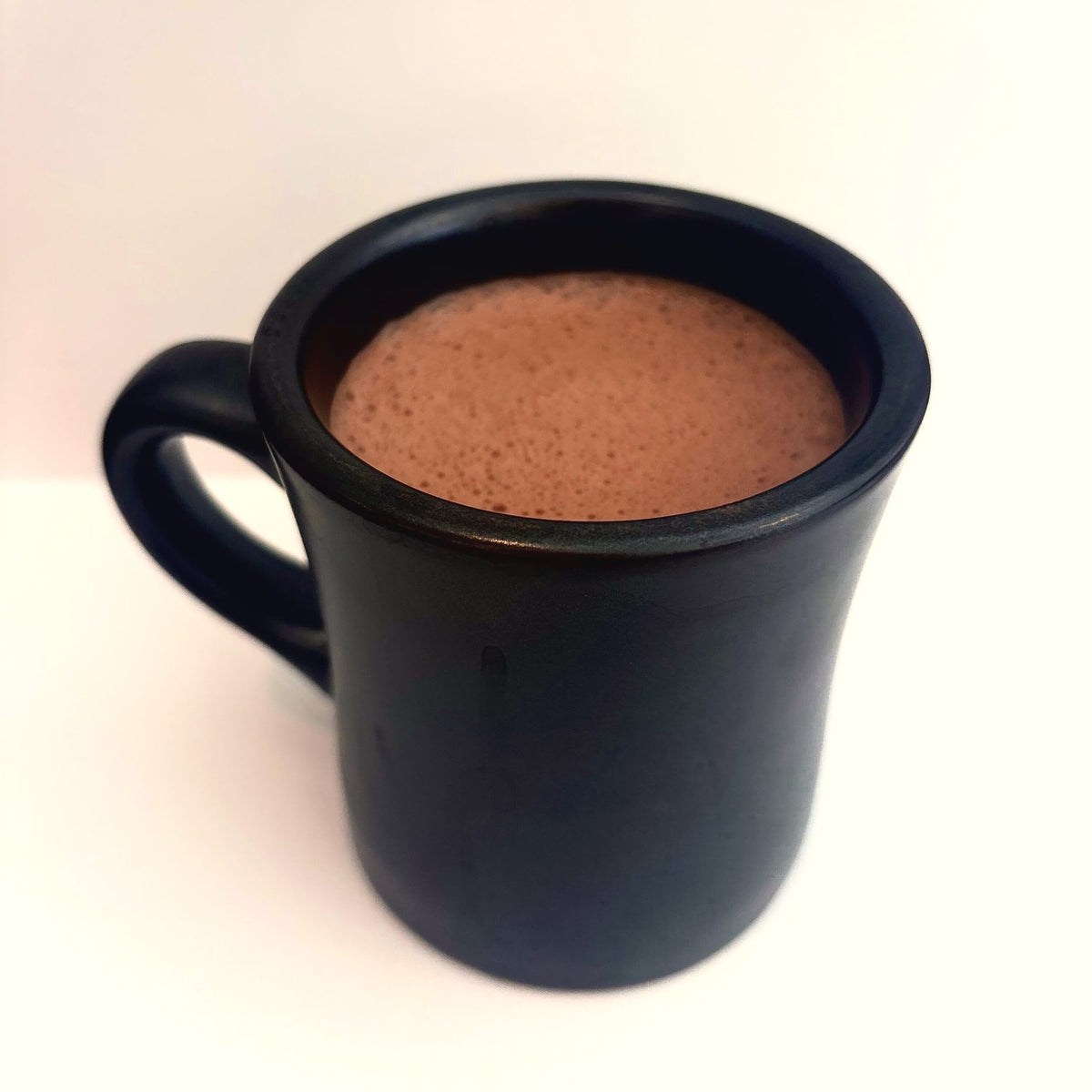 A black mug filled with Oro drinking chocolate