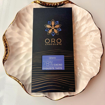 Oro Opayo 78% cacao bar in black packaging on a gold-rimmed white porcelain plate, seen from above