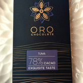 Close-up of the Oro Tuma 78% cacao chocolate bar label and the gold Oro flower mark on the black pack